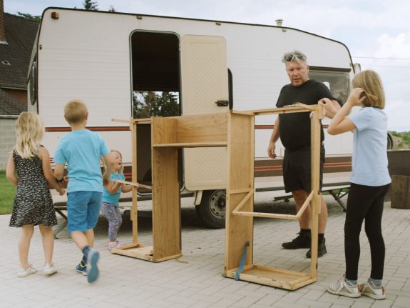 Volwassene en twee kinderen werken aan de houten frame voor een caravan.